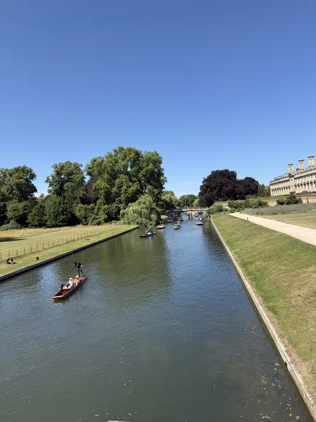 A punt approaching a historic stone bridge on the River Cam, Cambridge College Backs