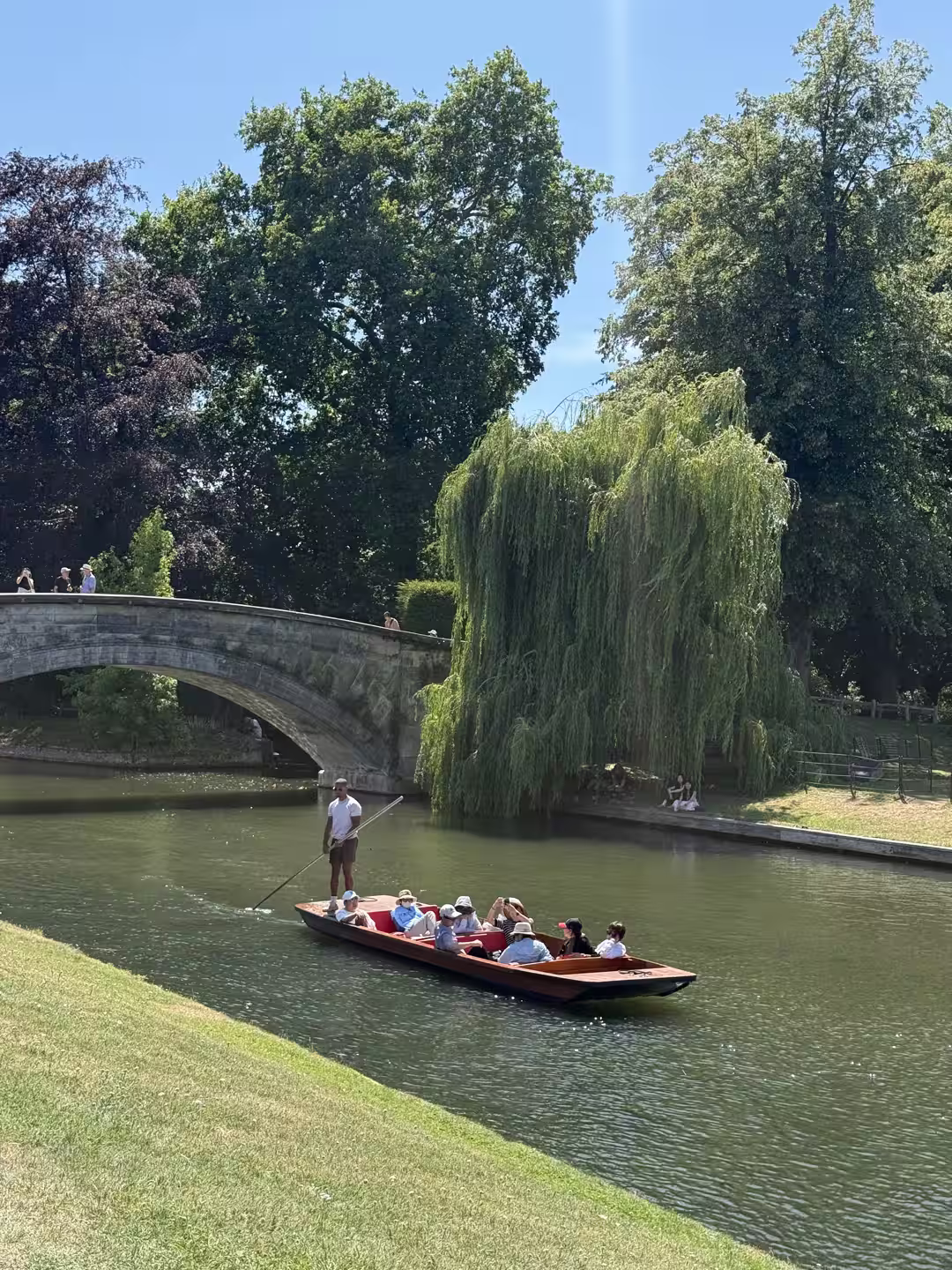 Punts gliding under a stone bridge on the Cambridge College Backs